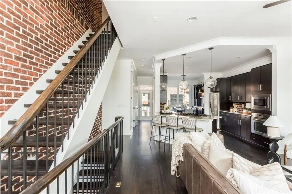 Open concept main level with floating staircase and grand kitchen with stainless steel appliances and hardwood floors