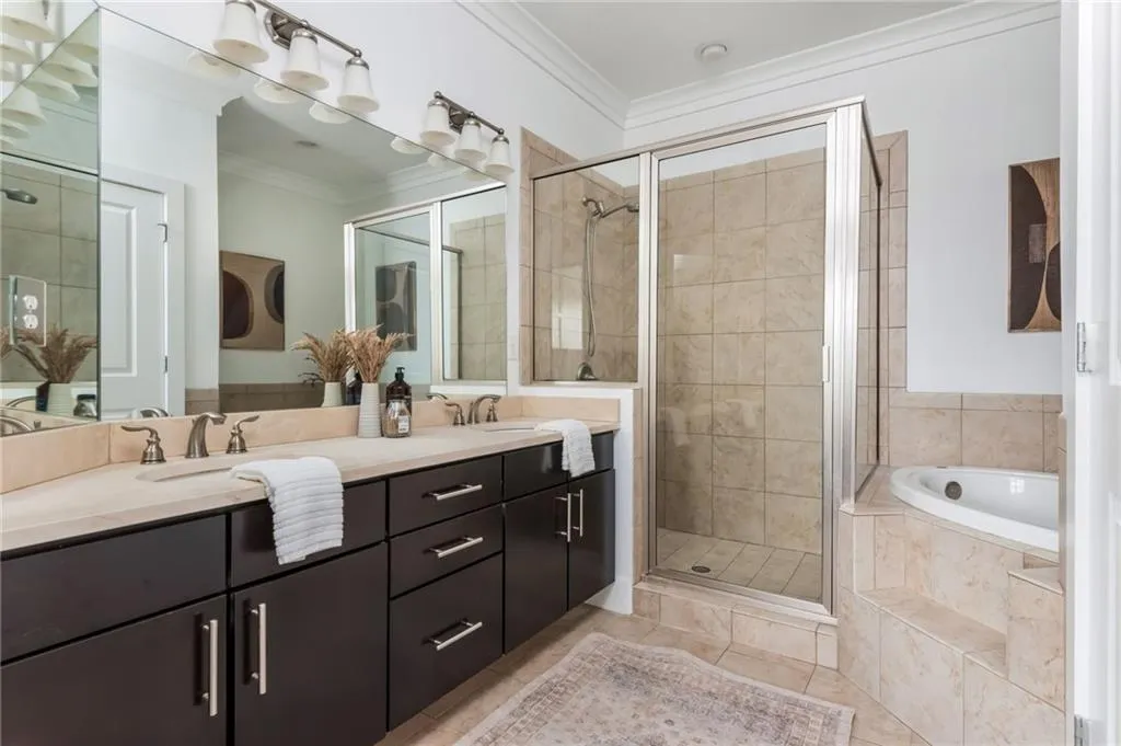 Primary bathroom with dual vanities, walk-in tiled shower and large soaking tub