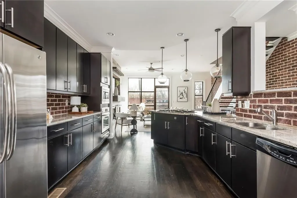 Large kitchen features brick backsplash, hardwood floors, stainless steel appliances and updated light fixtures.