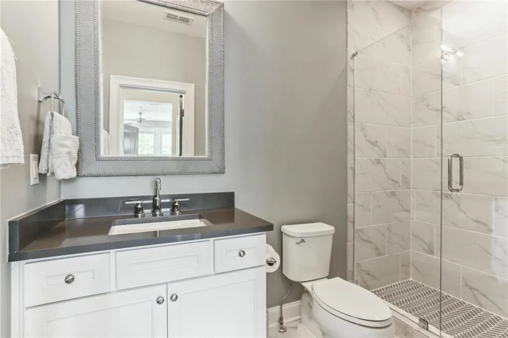 Bathroom featuring vanity, toilet, and a shower with shower door