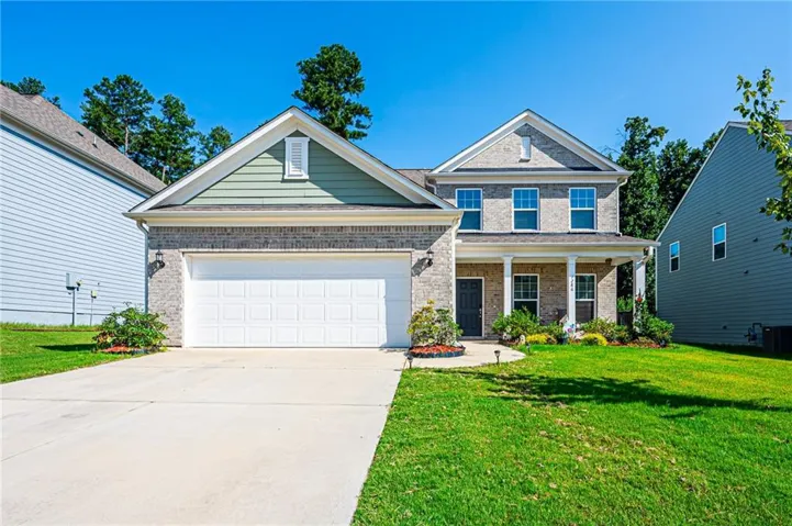 Two-story facade with brick and siding accents, featuring a covered front porch with white columns, a two-car garage, and a concrete driveway