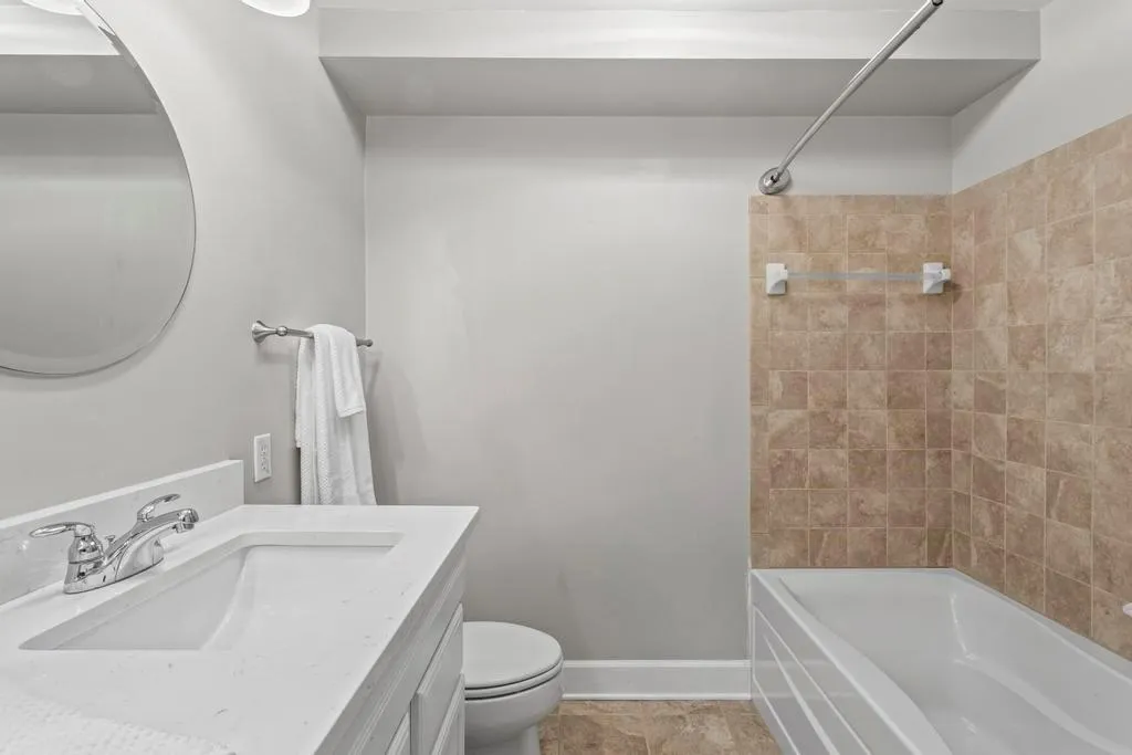 Full bathroom with large vanity, tiled shower / bath combo, tile flooring, and toilet