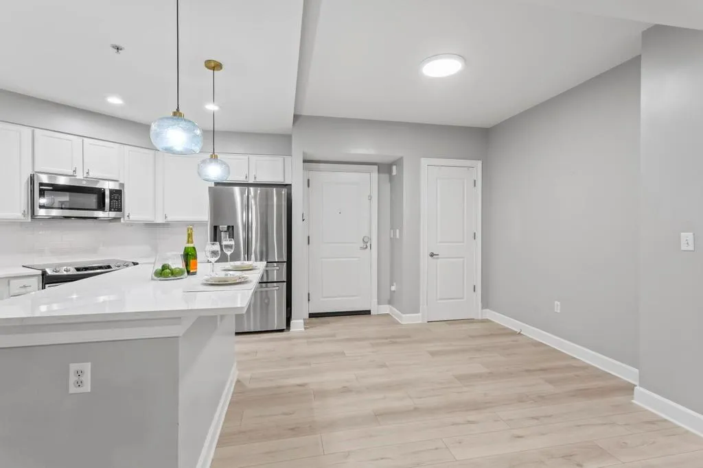 Kitchen featuring light hardwood / wood-style floors, decorative light fixtures, stainless steel appliances, and white cabinets