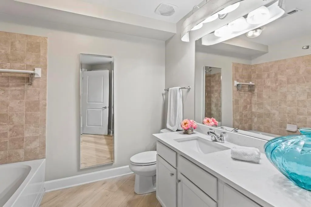 Full guest bathroom featuring tiled shower / bath, oversized vanity, and toilet