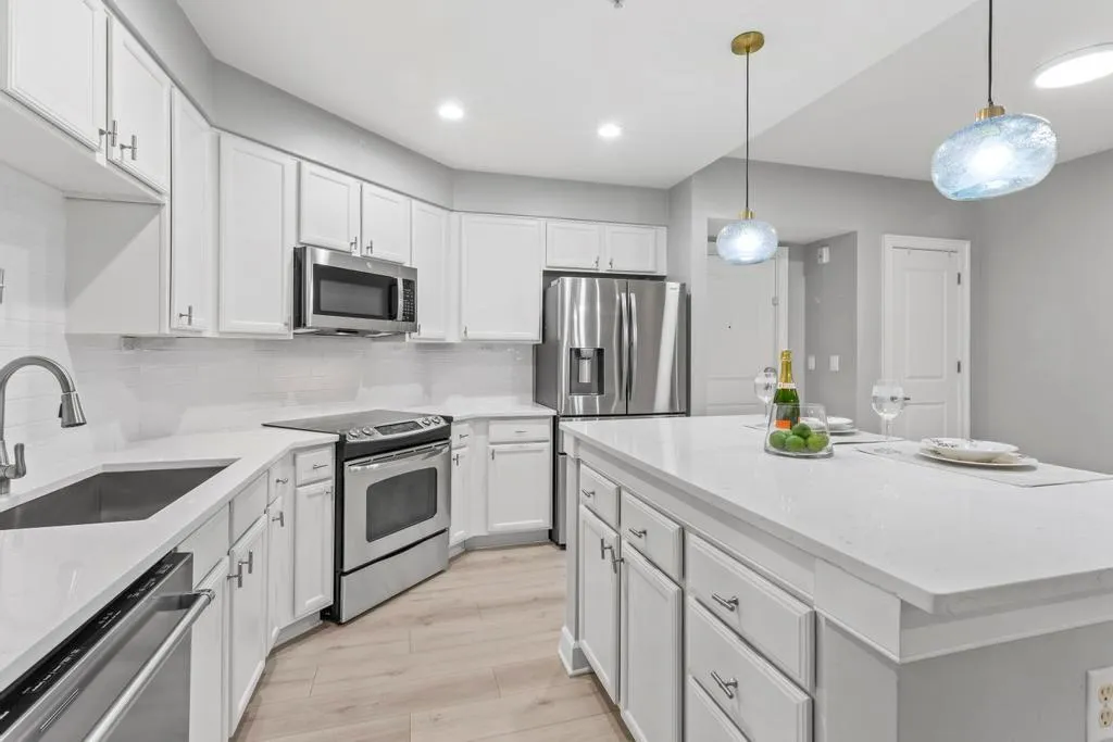 Kitchen featuring light hardwood / wood-style flooring, white cabinets, tasteful backsplash, stainless steel appliances, and pendant lighting