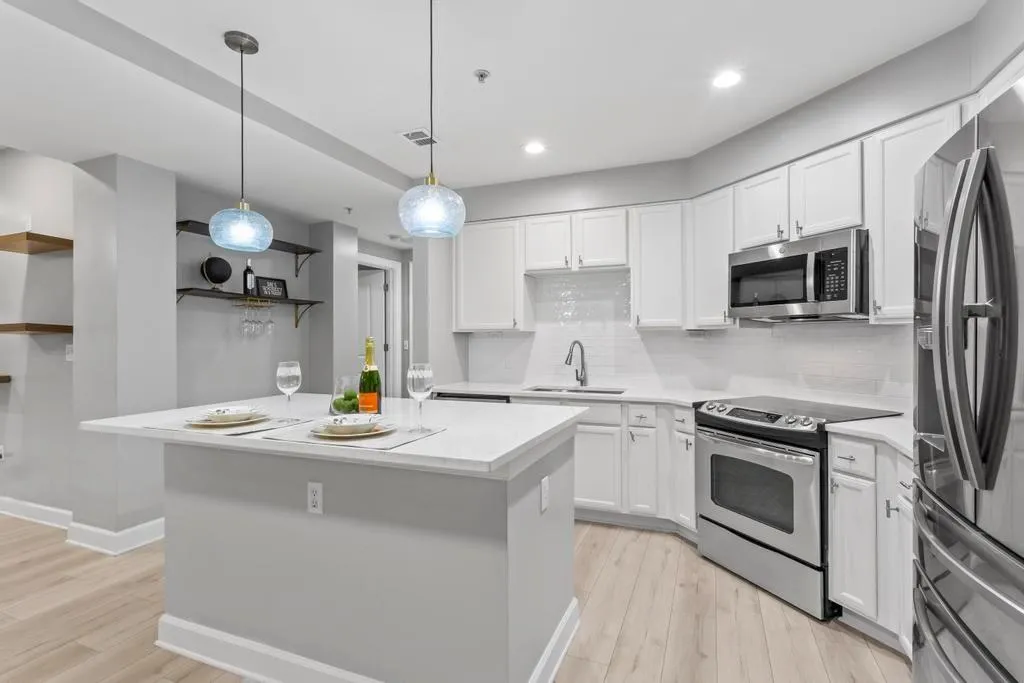 Kitchen featuring light hardwood / wood-style flooring, decorative light fixtures, stainless steel appliances, and white cabinets