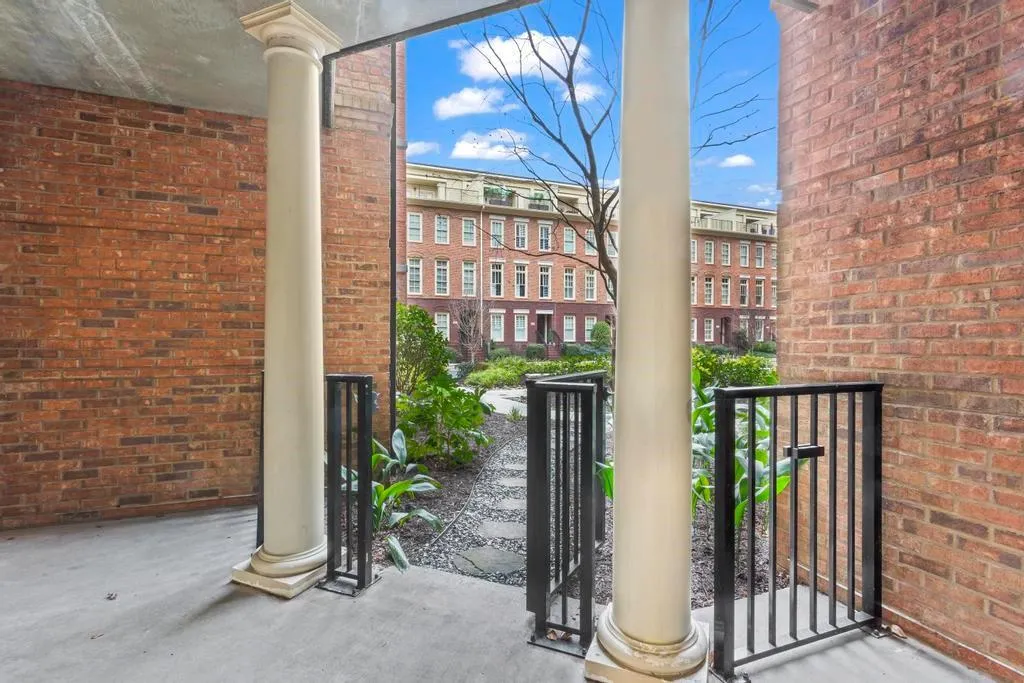 View of extra large covered patio with gate and pavers leading into courtyard