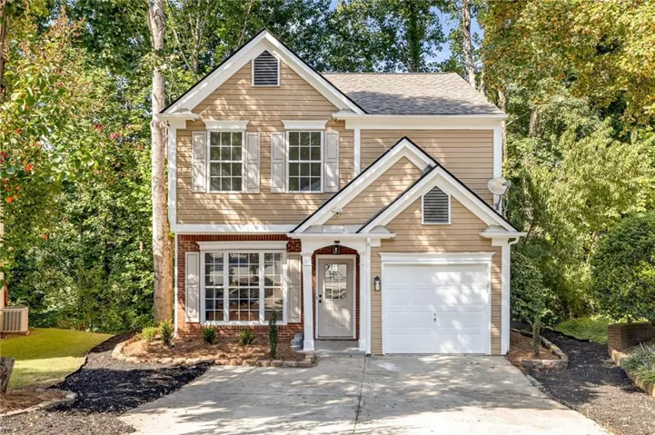 Two-story residence featuring a front-facing garage, brick and siding exterior, multi-pane windows with shutters, and a covered entry