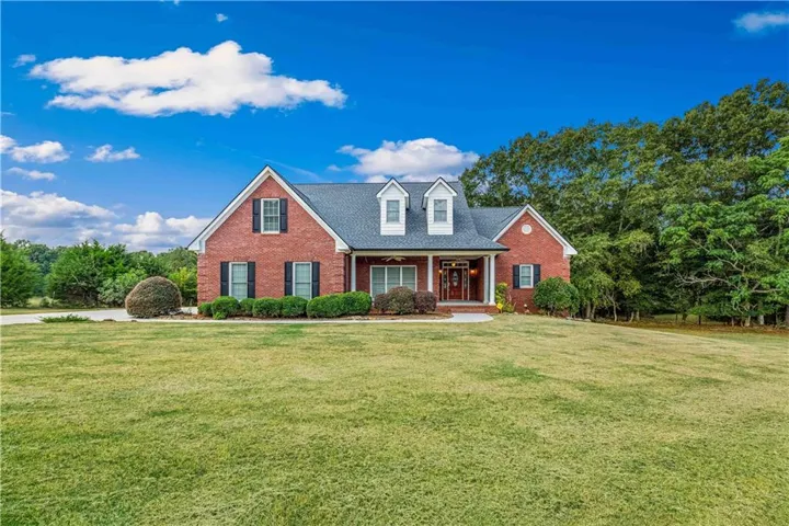 Brick exterior with black shutters and a covered front porch featuring white columns