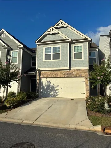 Multi-level exterior featuring light blue shake siding, a stone facade, and white trim accents