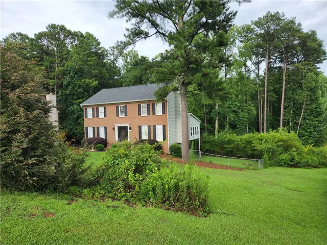Colonial inspired home featuring view of wooded area