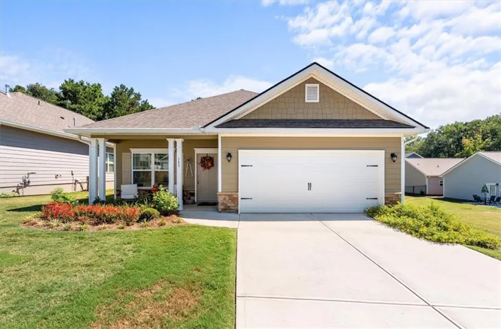 Single-story residence featuring a two-car garage, covered entry with columns, and a landscaped front yard with concrete driveway