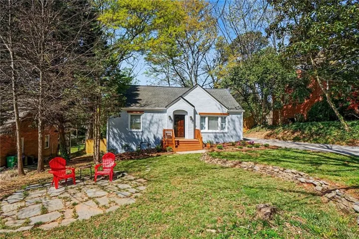 Light blue exterior, dark wood entry door, natural wood steps, white window trim, and a flagstone patio