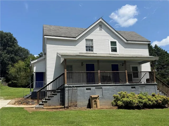 Two-story residence with white siding and a covered front porch featuring dark wood railings