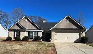 Single-story residence featuring a two-car garage, brick and vertical siding exterior, and a gabled roofline