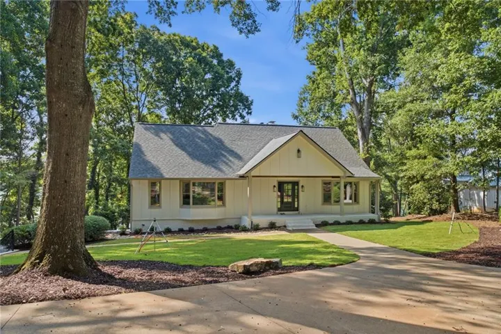 Traditional residence featuring a prominent gabled roofline, board and batten siding, and an expansive front yard with mature trees