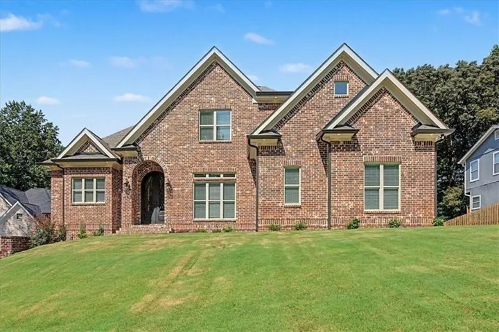 Brick exterior with multiple gables, arched entry, and a symmetrical facade