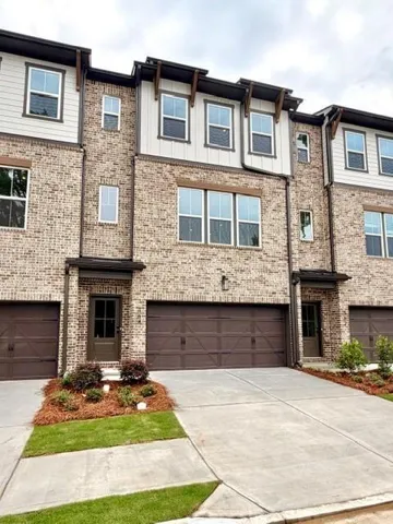 Multi-story townhome featuring a brick facade with horizontal siding accents