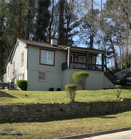 View of front of home featuring a chimney, covered porch, and a front lawn