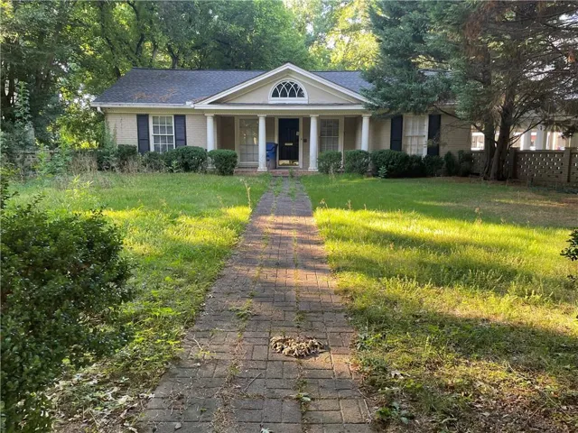 Greek revival house featuring a porch, a shingled roof, and brick siding