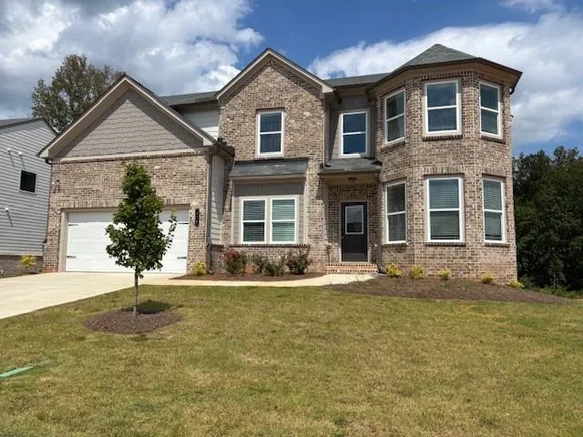 Brick exterior with two-car garage, multiple windows, and a prominent bay window feature