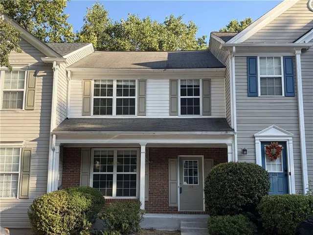 Two-story residence featuring light-colored siding, contrasting shutters, and a covered front entry