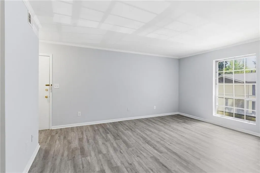 Empty room featuring light wood-type flooring and ornamental molding