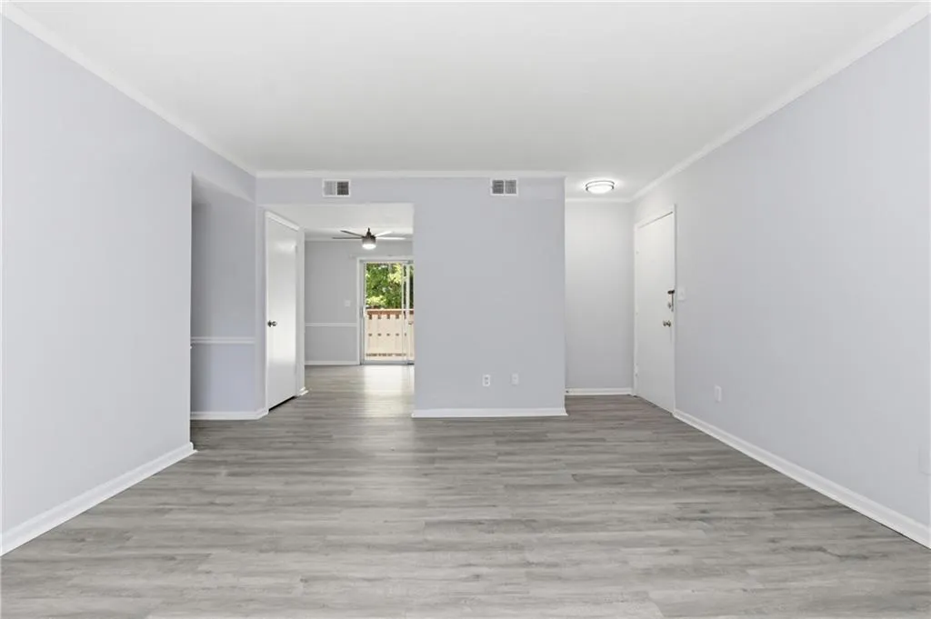 Empty room featuring light wood-type flooring, crown molding, and ceiling fan