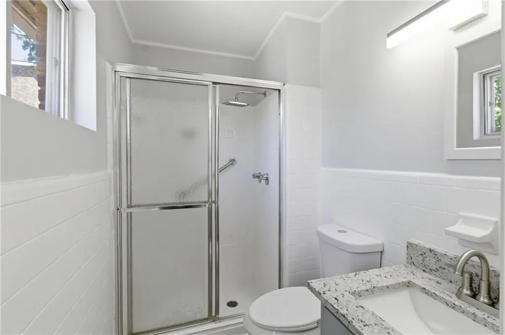 Bathroom with tile walls, a wainscoted wall, vanity, and a shower stall