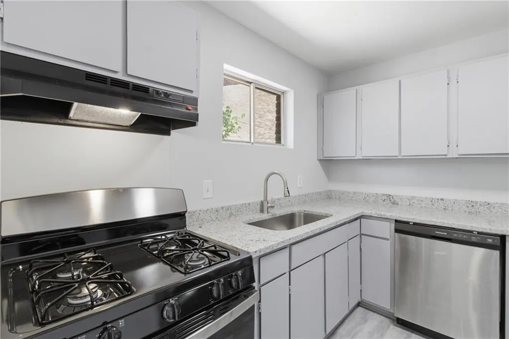 Kitchen featuring stainless steel appliances, light stone counters, and gray cabinets