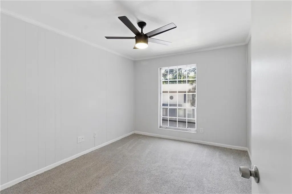 Carpeted spare room with crown molding and ceiling fan