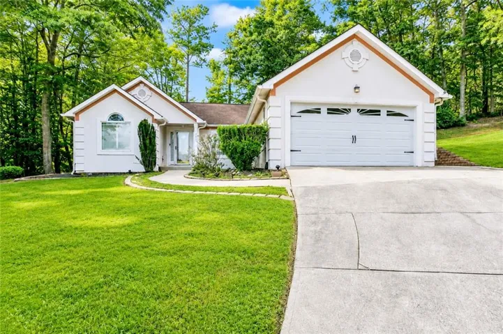 White exterior with a two-car garage, concrete driveway, and curved walkway