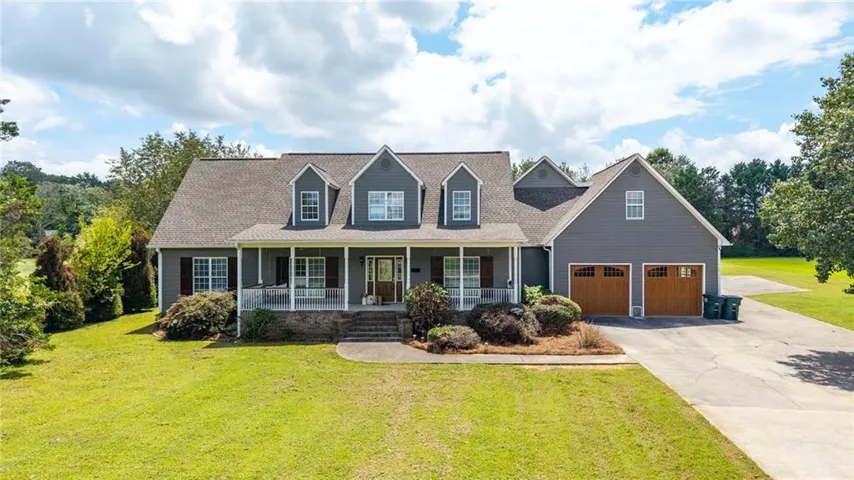 Two-story residence featuring dormer windows, a full front porch, and a two-car garage with wood-finish doors
