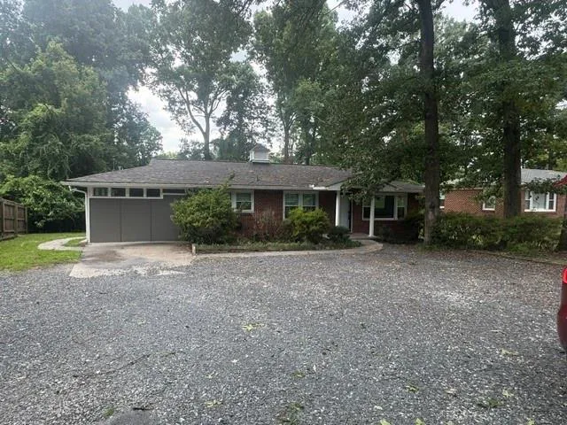 Brick exterior with white trim, a gabled roof, and a gravel driveway