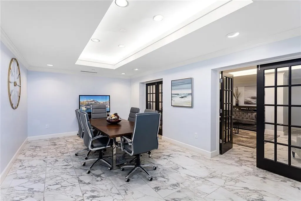 Recessed tray ceiling, stone-finish tile flooring, and black-framed French doors