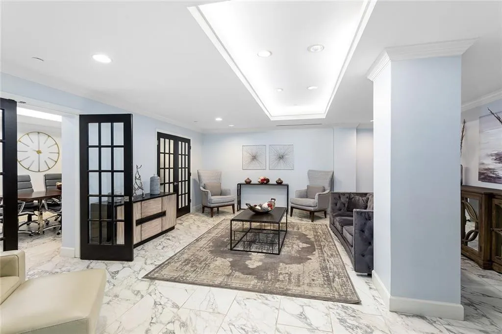 Tray ceiling with recessed lighting, stone-finish tile flooring, and black-framed glass panel doors