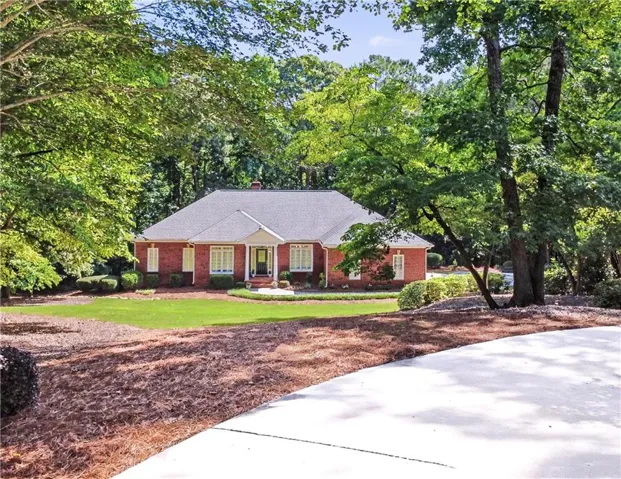 Brick exterior home featuring a gabled roof, white trim accents, and a covered porch entry