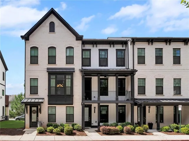 Multi-story townhouse exterior featuring a painted brick facade, black trim, and a prominent bay window