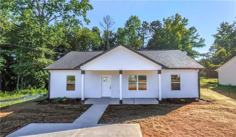 Freshly constructed single-story residence featuring a clean-lined gable roof, white exterior siding, and a covered front porch with multiple entry points