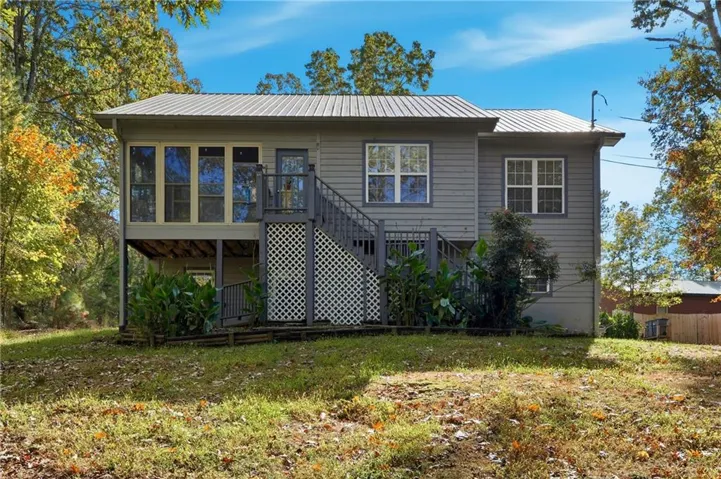 Front of house featuring stairway, a metal roof, a sunroom, and a wooden deck