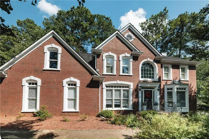 Brick exterior featuring white architectural trim, multiple gabled rooflines, an arched window above the entry, and a bay window