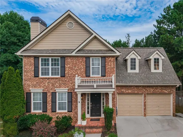 Brick exterior with tan siding accents, featuring a covered front entry, an upper-level balcony, and a two-car garage