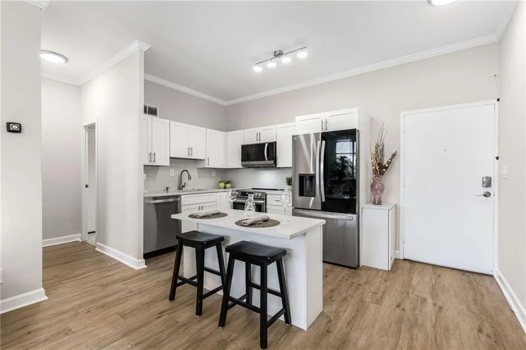 Kitchen featuring ornamental molding, stainless steel appliances, white cabinets, a kitchen breakfast bar, and tasteful backsplash