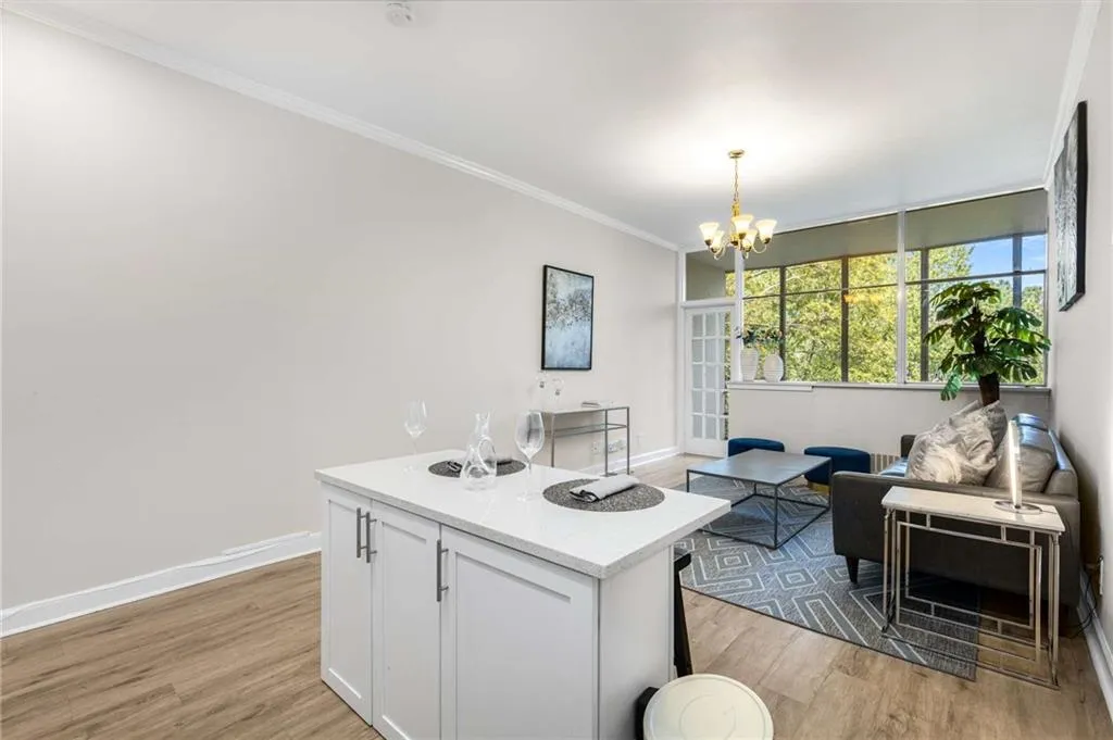 Kitchen with white cabinets, crown molding, light wood-style floors, open floor plan, and hanging light fixtures