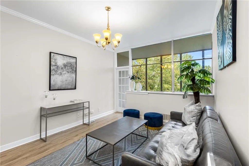 Living room featuring wood finished floors, crown molding, and a chandelier