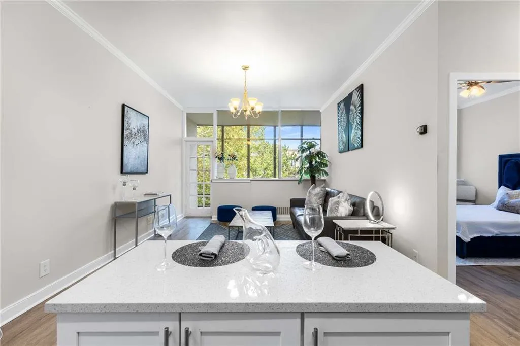 Kitchen featuring light wood-style floors, crown molding, light stone countertops, white cabinets, and a center island