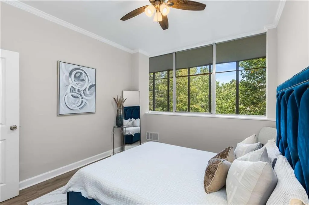 Bedroom with ornamental molding, multiple windows, wood finished floors, and ceiling fan