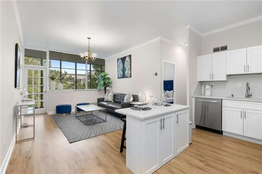 Kitchen featuring ornamental molding, a kitchen bar, open floor plan, white cabinetry, and dishwasher