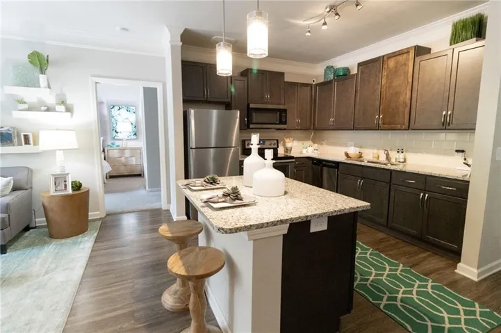 Kitchen with dark hardwood / wood-style floors, dark brown cabinets, a kitchen bar, and stainless steel appliances