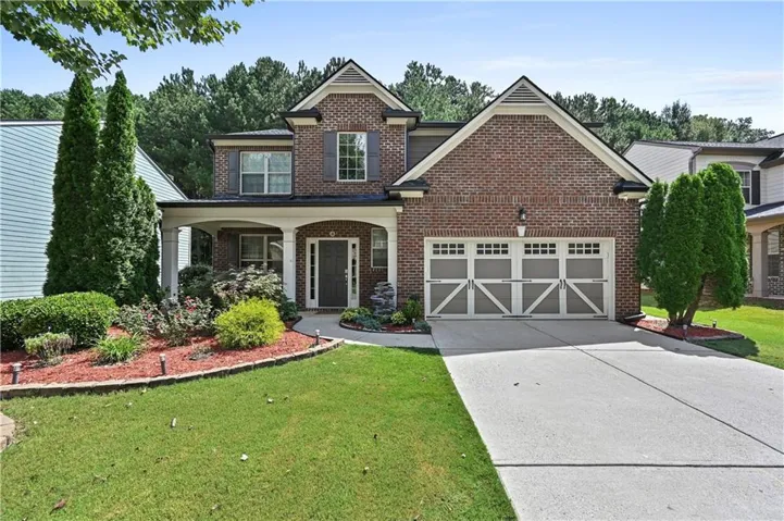 Brick facade with gabled roof lines, featuring a covered front porch with white columns